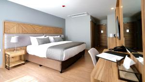 Canalis Suvarnabhumi Airport Hotel في لاكريبنغ لاد: غرفة نوم مع سرير ومكتب مع جهاز كمبيوتر