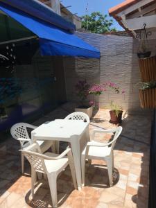 a white table and chairs on a patio with a blue umbrella at Pousada Recanto do Arraial do Cabo in Arraial do Cabo
