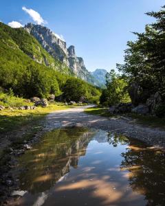 a large puddle of water on a road with mountains at Guest House Kollata in Vusanje