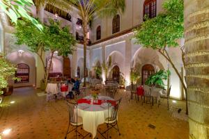 een kamer met tafels en stoelen in een gebouw met bomen bij Riad Amina in Marrakesh