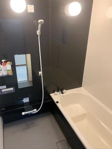 鹿兒島的住宿－ガナダン中央駅 1f 無料駐車場，带浴缸、水槽和镜子的浴室