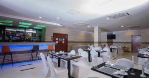 un restaurante con mesas y sillas blancas y un bar en Hôtel La Rose Blanche Korhogo, en Korhogo
