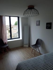 ジョネ・クランにあるFuturoscope appartement 40m2 à 7 min du parcのベッドと椅子2脚と窓のある寝室