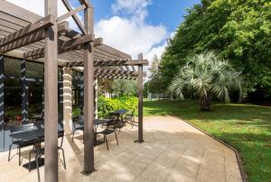 une pergola en bois avec des tables et des chaises sur une terrasse dans l'établissement Hôtel Oceania Nantes Aéroport, à Bouguenais