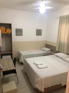 Cette chambre comprend deux lits, une table, une table et des chaises. dans l'établissement Hotel Araçari, à Araçariguama