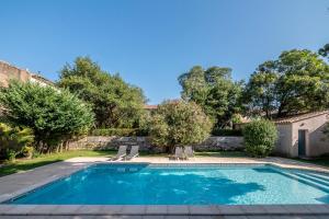 - une piscine dans une cour avec 2 chaises longues dans l'établissement Mas d'Escattes, à Nîmes