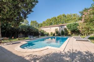 - une piscine dans une cour avec des chaises et un bâtiment dans l'établissement Mas d'Escattes, à Nîmes