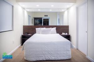 a bedroom with a large white bed with a large mirror at Crystal Beach Suites Oceanfront Hotel in Miami Beach
