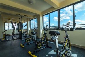 ein Fitnessraum mit mehreren Heimtrainern in einem Raum mit Fenstern in der Unterkunft Ruthys Apartment in Nairobi