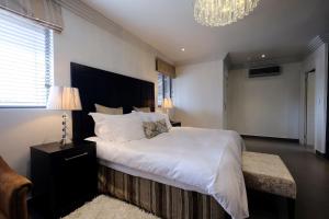 um quarto com uma grande cama branca e um lustre em Villa Moyal em Joanesburgo