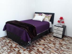 1 dormitorio con cama morada y mesita de noche en B&B La Casa del Turista, en Lima