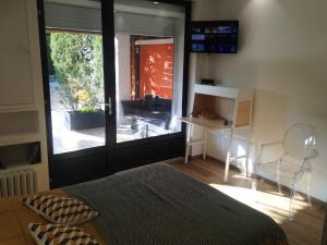 1 dormitorio con cama, escritorio y puerta corredera de cristal en CHAMBRE CENTRE VILLE Coté soleil en Forcalquier