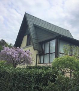 a house with a black roof and purple lilacs at Holiday Home Magnolia in Trakošćan