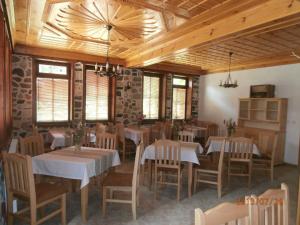 una sala da pranzo con tavoli, sedie e soffitti in legno di Hotel Mitnitsa and TKZS Biliantsi ad Arda