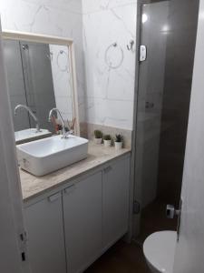 y baño con lavabo, espejo y aseo. en Farol Barra flat 412, en Salvador