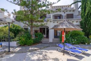 a group of chairs and an umbrella in front of a building at Casa Billarose - Lovely House overlooking pool & walking distance to the Beach and Restaurants in Cabo Roig