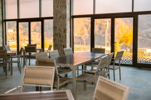 ein Esszimmer mit einem Tisch, Stühlen und Fenstern in der Unterkunft Yurd Hotel in Qax