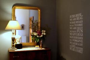un espejo en una pared con un jarrón de flores y una lámpara en Ay Home B&B, en Bolonia