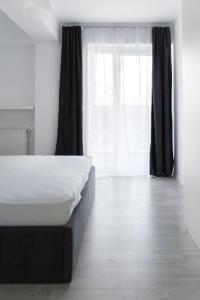 a bedroom with a bed and a large window at Airport Residence - Apartment across from Otopeni Airport in Otopeni