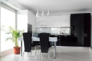 una cocina con armarios en blanco y negro, mesa y sillas en Airport Residence - Apartment across from Otopeni Airport en Otopeni