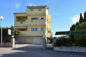 a yellow building with a garage in front of it at Apartments Sestan in Zadar