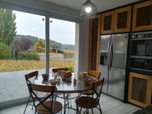 a dining room with a table and chairs and a large window at gîte coeur de champagne in Romery