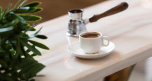 a cup of coffee sitting on a white table at Quba Inn Hotel in Jazan