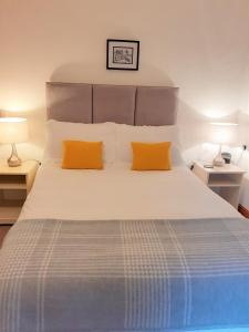 Wye Cottage في بيلث ويلز: غرفة نوم مع سرير كبير مع وسادتين برتقاليتين