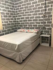 uma cama num quarto com uma parede de tijolos em Casa 3 quartos Bombinhas lado Mar ou AP de 2 quartos em Bombinhas