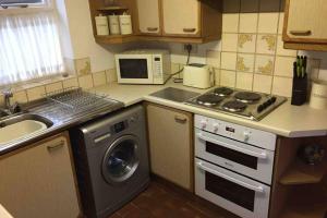 een keuken met een wasmachine en een magnetron bij Rose Cottage in Ludham