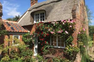 een oud bakstenen huis met bloemen erop bij Rose Cottage in Ludham