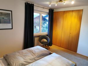 um quarto com uma cama, uma janela e uma cadeira em Haus Pierzinger em Wörgl