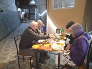 grupa ludzi siedzących przy stole jedzących jedzenie w obiekcie Apple House w mieście Shimla