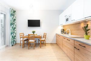 kuchnia ze stołem i krzesłami oraz telewizorem w obiekcie STEAM PARK Krakow Apartment w Krakowie