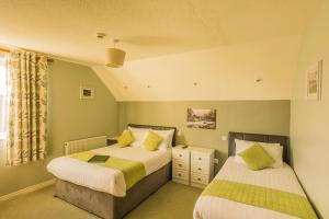 a bedroom with two beds and a window at The Pipers Rest in Doolin