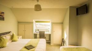 a room with two beds and a desk and a window at The Pipers Rest in Doolin