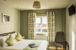 a bedroom with a bed and a window and a chair at The Pipers Rest in Doolin