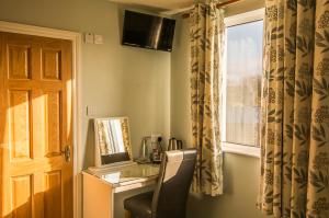 a room with a desk with a chair and a window at The Pipers Rest in Doolin