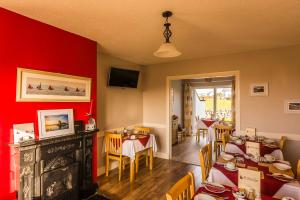 a restaurant with red walls and tables and chairs at The Pipers Rest in Doolin