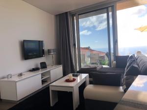 Una sala de estar con un sofá y una ventana grande. en Villa Pinheira II, en Estreito da Calheta