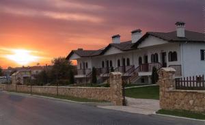 a large white house with a sunset in the background at Village Naiades in Kastoria