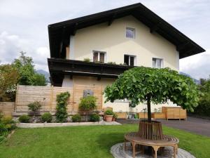 uma árvore em frente a uma casa com um banco em Haus Pierzinger em Wörgl