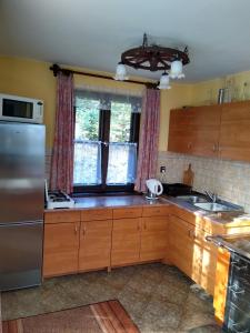 a kitchen with wooden cabinets and a stainless steel refrigerator at Kolędówka Rest in Zawoja