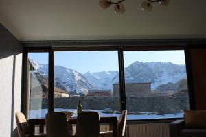 a dining room with a view of mountains from a window at Green Apartment in Kazbegi