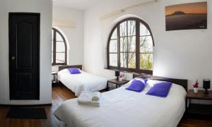 two beds in a room with two windows at El Museo Hotel Boutique in La Paz