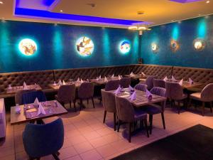 a dining room with tables and chairs and blue walls at Achilleon III in Geesthacht