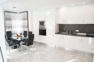 een keuken met witte kasten en een tafel met stoelen bij Playa de Las Americas Luxury Home in Playa de las Americas