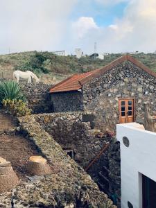 Erese的住宿－Casita Pedro González，一座石头房子,后面有一只白马
