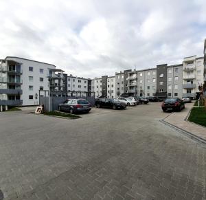 un aparcamiento con coches estacionados frente a los complejos de apartamentos en GM Apartament Szczecin, en Szczecin