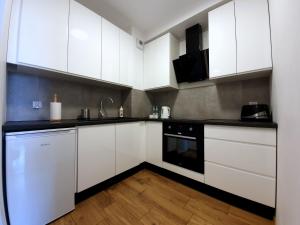 una cocina con armarios blancos y un aparato negro en GM Apartament Szczecin, en Szczecin